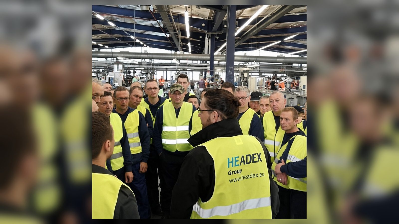 Dovydas Liaudanskas in a Headex Group factory briefing with workers in high visibility vests